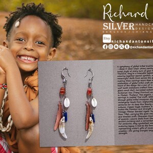 May include: Silver earrings with a tribal design. The earrings have red, white, and blue beads, shells, and bone pendants. The image includes text: Richard Anton Silver, Handcrafted Jewelry.