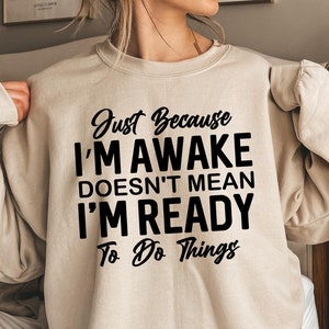 Puede incluir: Sudadera beige con texto negro que dice "Just Because I'm Awake Doesn't Mean I'm Ready To Do Things".