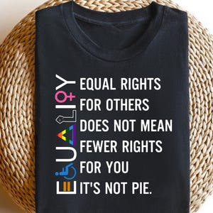 Op de afbeelding: Zwart T-shirt met witte tekst die luidt: "EQUALITY EQUAL RIGHTS FOR OTHERS DOES NOT MEAN FEWER RIGHTS FOR YOU IT'S NOT PIE."