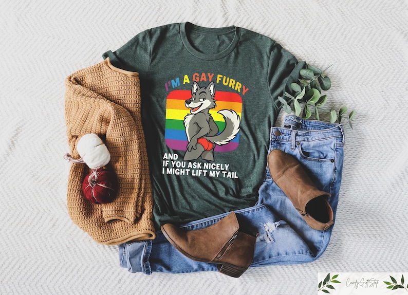 May include: A dark green t-shirt with the text "I'M A GAY FURRY" and a cartoon wolf graphic. The image includes a tan sweater, blue jeans, and brown boots. A red and white decorative item is also present.