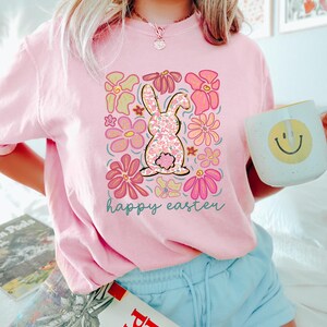 Peut inclure: T-shirt rose avec un motif floral repr&eacute;sentant un lapin et le texte "happy easter".
