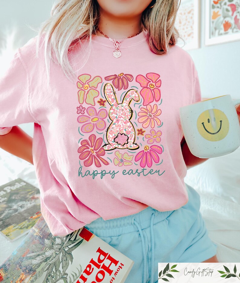 Peut inclure: T-shirt rose avec un motif floral repr&eacute;sentant un lapin et le texte "happy easter".