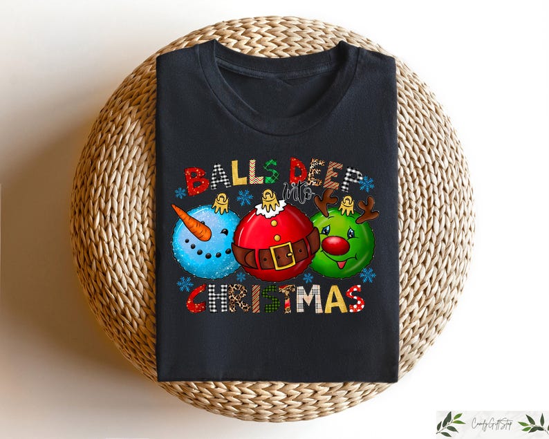 以下が含まれることがあります： クリスマスをテーマにしたグラフィックが特徴の黒いTシャツ。デザインには、雪だるま、サンタ、トナカイの3つのオーナメント型のキャラクターが含まれています。「BALLS DEEP CHRISTMAS」の文字がオーナメントの上と下に表示されています。