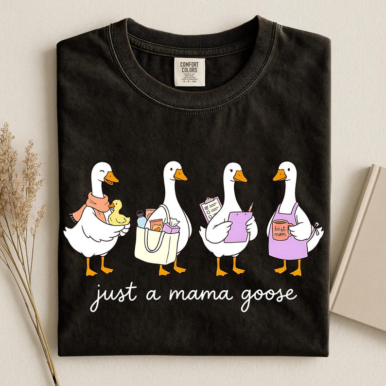 May include: Black t-shirt with a graphic of four cartoon geese, each with a different accessory. The text "just a mama goose" is written in cursive below the geese. The shirt has a Comfort Colors tag.