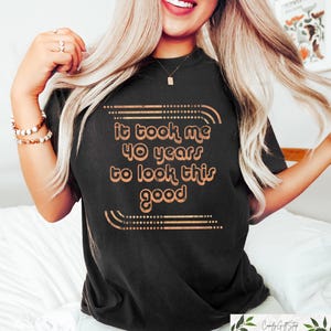 May include: Black t-shirt with a gold graphic that says "It took me 40 years to look this good".