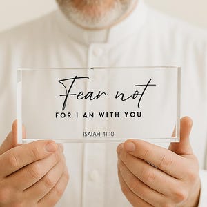 May include: A clear acrylic block with the words "Fear not, for I am with you" in black script. The text "Isaiah 41.10" is below the quote. The block is held by a person.