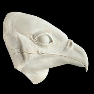 May include: A white plaster sculpture of a bird's head with a closed eye and a beak.