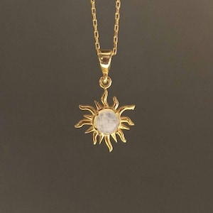 May include: A gold chain necklace with a sun pendant featuring a round moonstone.