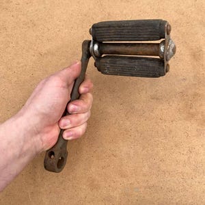 May include: A vintage bicycle pedal with a metal arm and three wooden treadles. The pedal is rusty and shows signs of wear.