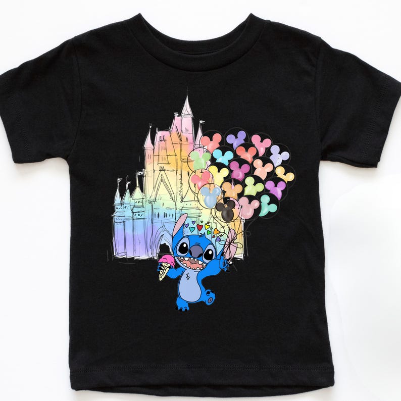 Puede incluir: Camiseta negra con una ilustraci&oacute;n de dibujos animados de Stitch sosteniendo un helado y globos. Un castillo colorido est&aacute; en el fondo. Los globos tienen forma de cabezas de Mickey Mouse.