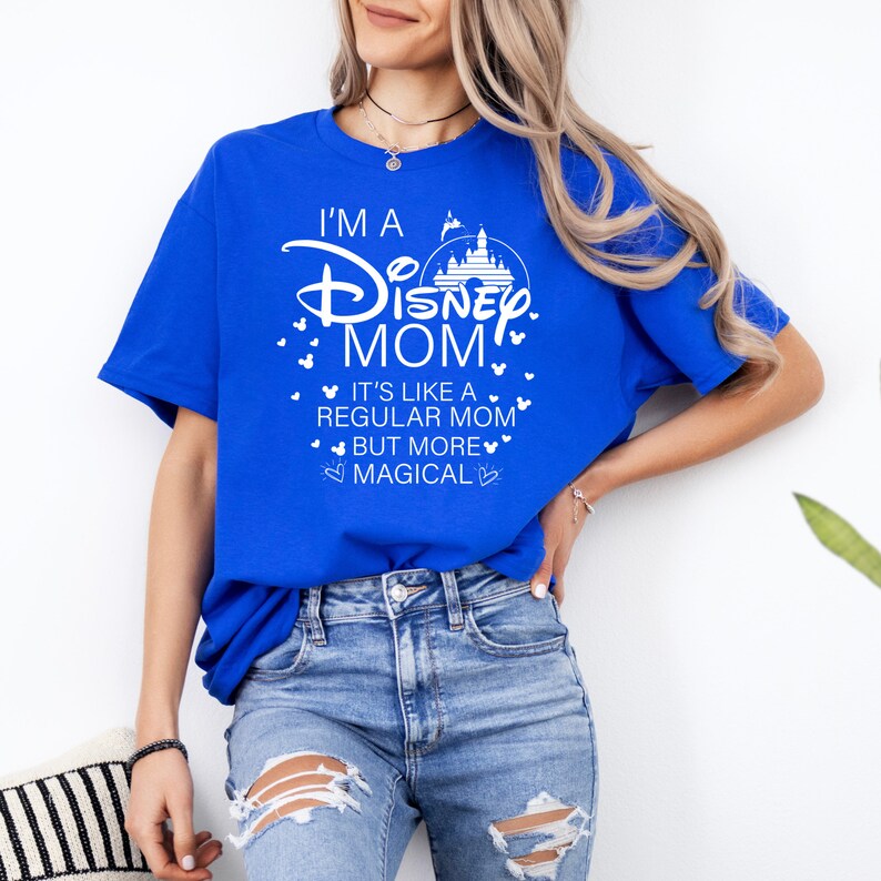 May include: Royal blue t-shirt with the text "I'M A Disney MOM" in white, along with a castle graphic and heart accents. The shirt also includes the phrase "IT'S LIKE A REGULAR MOM BUT MORE MAGICAL".