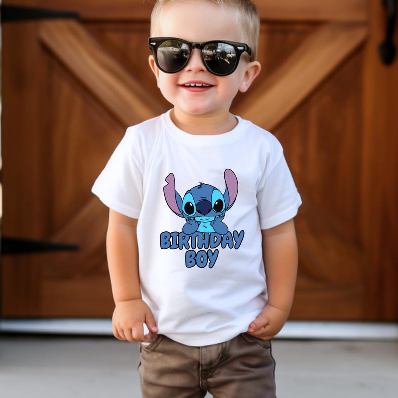 May include: A white t-shirt with a blue Stitch character from the Disney movie Lilo & Stitch. The shirt says "Birthday Boy" in blue letters.