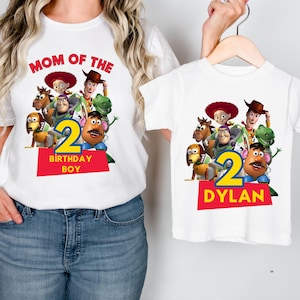 May include: White t-shirts featuring a colorful graphic of Toy Story characters. One shirt reads "MOM OF THE" and "BIRTHDAY BOY" with a number 2. The other shirt has the number 2 and the name "DYLAN".