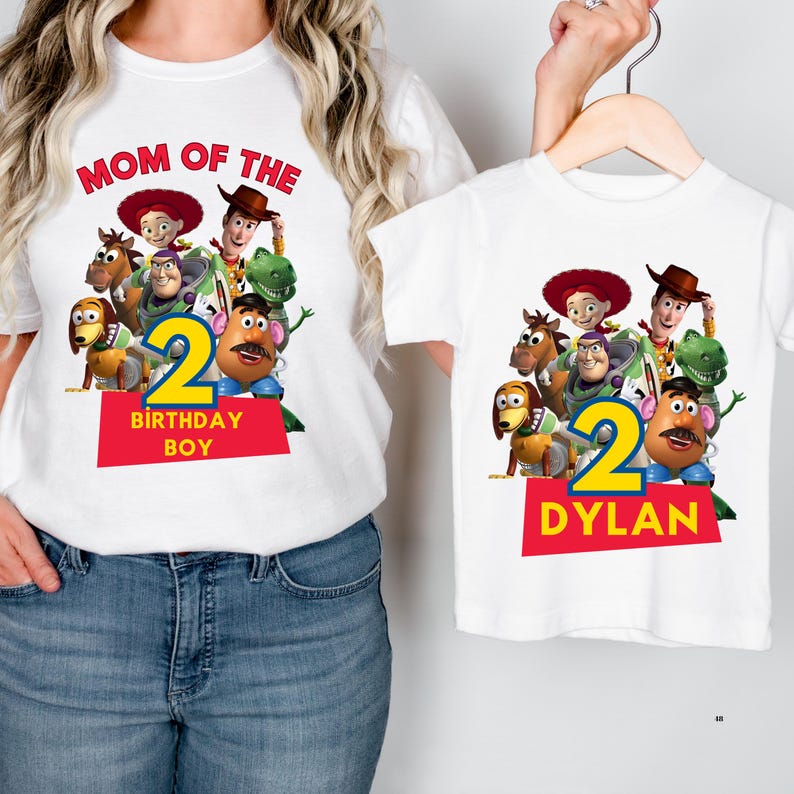 May include: White t-shirts featuring a colorful graphic of Toy Story characters. One shirt reads "MOM OF THE" and "BIRTHDAY BOY" with a number 2. The other shirt has the number 2 and the name "DYLAN".