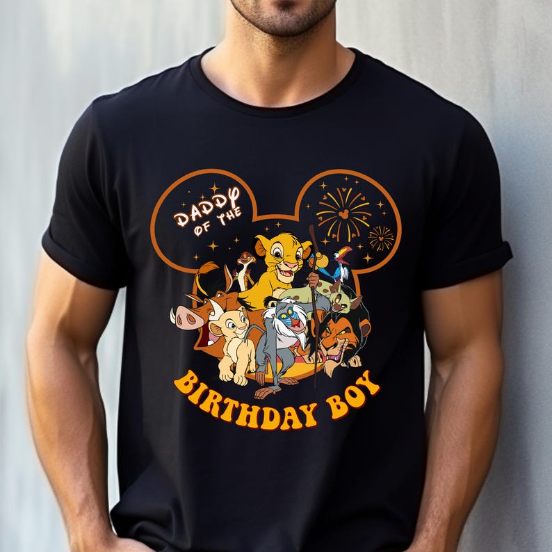 May include: Black t-shirt featuring a graphic of characters from The Lion King, including Simba, Timon, Pumbaa, and Scar. The design includes the text "Daddy of the Birthday Boy" in orange, set within a Mickey Mouse ear outline.