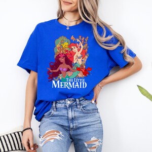 Puede incluir: Una camiseta azul real con un estampado gr&aacute;fico de Ariel, la Sirenita, y sus amigos. El texto "The Little Mermaid" est&aacute; impreso debajo del gr&aacute;fico.