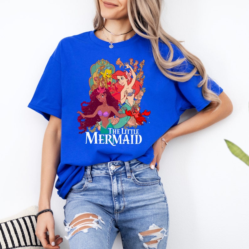 Puede incluir: Una camiseta azul real con un estampado gr&aacute;fico de Ariel, la Sirenita, y sus amigos. El texto "The Little Mermaid" est&aacute; impreso debajo del gr&aacute;fico.