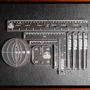 May include: A set of clear acrylic leathercraft templates by Castillo Heritage Crafts, including a long ruler with imperial and metric markings, a square, a circular grid, a corner radius tool, and four thin edge creasers with labeled widths.