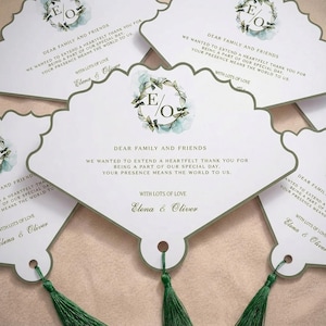 May include: White wedding thank you cards with a scalloped edge and green tassel. The cards feature the text "Dear Family and Friends" and "Elena & Oliver". The cards have a floral design with the letters "E" and "O".