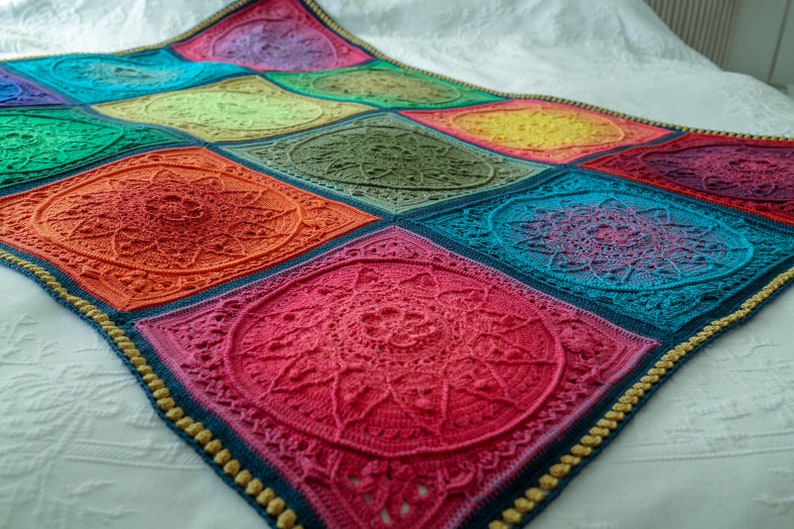 May include: A colorful crochet blanket with a mandala design in each square. The blanket is made with a variety of colors, including red, orange, yellow, green, blue, and purple. The blanket is bordered with a gold trim.