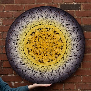 May include: A large, round crocheted mandala with a gradient of purple to yellow. The mandala is made with a delicate, lacy pattern and has a central motif of a star.