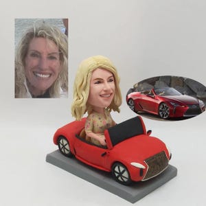 May include: A custom-made figurine of a woman with blonde hair driving a red convertible car. The figurine is made of polymer clay and is hand-painted.
