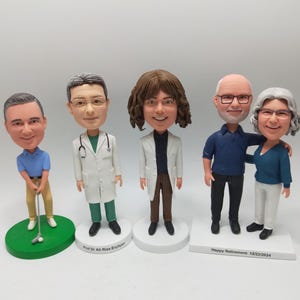 Op de afbeelding: Vier op maat gemaakte figuurtjes van mensen, elk met een unieke persoonlijkheid en outfit. De figuurtjes staan op individuele bases, met de tekst "Prof Dr Ali Riza Erciyes" op de ene basis en "Happy Retirement 12/22/2024" op de andere.