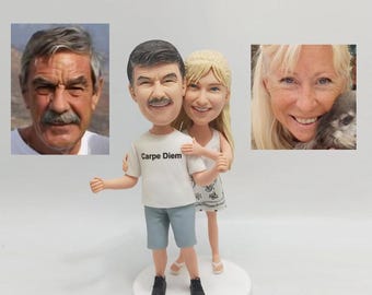 May include: A custom-made figurine of a couple, the man is wearing a white t-shirt with the text "Carpe Diem" printed on it, blue shorts, and black shoes. The woman is wearing a white dress and white shoes. The figurine is on a white base.