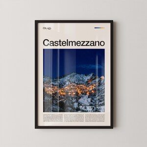 Könnte beinhalten: Gerahmtes Poster mit der Stadt Castelmezzano, Italien, bei Nacht. Das Bild zeigt eine Berglandschaft mit den Lichtern der Stadt, die die schneebedeckten Gipfel beleuchten. Das Poster trägt den Text "Castelmezzano" in großer Schrift und zusätzlichen Text am unteren Rand.