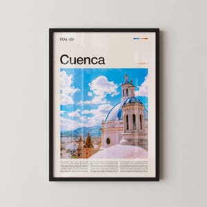 May include: Framed poster featuring a photograph of Cuenca, Ecuador, with a blue and white domed building under a bright blue sky with fluffy white clouds. The word "Cuenca" is printed in large black letters, with additional text at the top and bottom.
