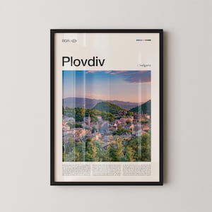 May include: Framed art print featuring the city of Plovdiv, Bulgaria. The image showcases a scenic view of the city with a mountain backdrop, under a blue and orange sky. The print includes the city name and country.