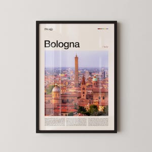 May include: Framed art print featuring a cityscape of Bologna, Italy, with the city's name in large font. The image showcases the iconic Asinelli Tower and other historic buildings with red rooftops. The print is in a black frame.