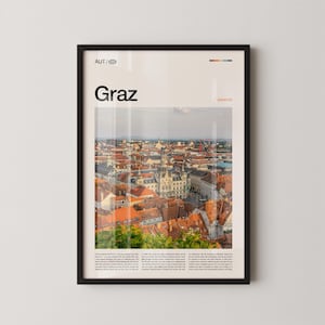 Könnte beinhalten: Gerahmter Druck mit einer Stadtansicht von Graz, Österreich, mit roten Ziegeldächern und historischen Gebäuden. Der Druck enthält den Stadtnamen "Graz" mit dem Text "AUT" und "austria". Das Bild befindet sich in einem schwarzen Rahmen.
