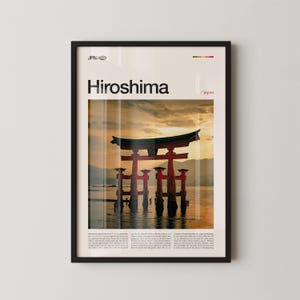 Puede incluir: Impresión artística enmarcada que presenta la icónica puerta torii roja del santuario de Itsukushima en Hiroshima, Japón, con un cielo al atardecer. La palabra "Hiroshima" está impresa en negrita, en letras negras sobre la imagen.