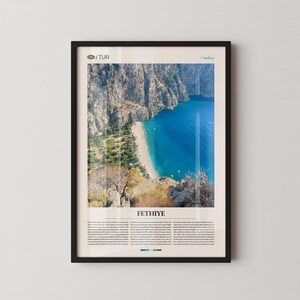 May include: Framed print featuring a scenic view of Fethiye, Turkey, with a turquoise bay and a sandy beach. The print includes the text "FETHIYE" at the bottom, with additional text below. The frame is black.