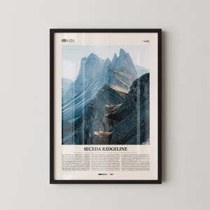 Puede incluir: Impresión enmarcada de la cordillera Seceda Ridgeline en Italia. La imagen muestra una vista panorámica de picos irregulares en tonos azules y grises, con un cielo despejado. La impresión está en un marco negro.