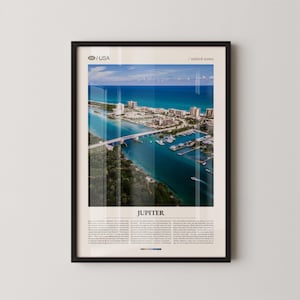 Könnte beinhalten: Gerahmter Druck mit einer Luftaufnahme von Jupiter, Florida, mit einer Brücke, Gebäuden und Booten auf dem Wasser. Der Druck enthält den Text "Jupiter" und "USA / united states". Das Bild ist in einem schwarzen Rahmen gerahmt.
