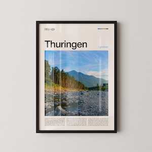 May include: Framed poster featuring a scenic view of Thuringen, Germany. The image showcases a riverbed with a mountain range in the background, under a blue sky. The word "Thuringen" is printed in bold, black letters at the top.