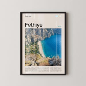 May include: Framed poster featuring a scenic view of Fethiye, Turkey, with a turquoise bay and a sandy beach. The poster has the word "Fethiye" in large font, with additional text at the top and bottom. The frame is black.