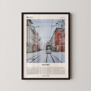 May include: Framed print of Erfurt, Germany, featuring a snowy street scene with a tram on the tracks. The buildings are a mix of red brick and light-colored facades. The text "ERFURT" is at the bottom.