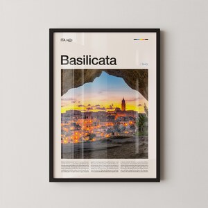 Könnte beinhalten: Gerahmter Druck mit dem Wort "Basilicata" über einer Stadtansicht bei Sonnenuntergang. Das Bild zeigt eine Stadt mit beleuchteten Gebäuden und einem hohen Turm, eingerahmt von einem natürlichen Felsbogen. Der Text "ITA / Italy" ist ebenfalls sichtbar.
