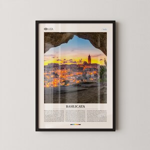 Könnte beinhalten: Gerahmter Druck von Matera, Italien, bei Sonnenuntergang, durch einen natürlichen Bogen betrachtet. Das Bild zeigt eine warme Farbpalette mit dem Text "BASILICATA" unten. Der Rahmen ist schwarz.