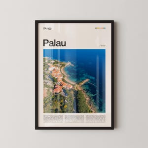 May include: Framed art print showing an aerial view of Palau, Italy, with a coastal town, blue sea, and a lighthouse. The word "Palau" is printed in large black letters. The print is in a black frame.