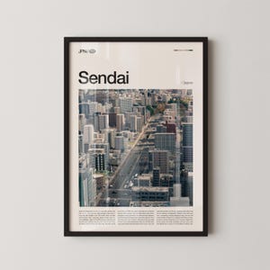 Puede incluir: Impresión enmarcada que presenta una vista en ángulo alto de Sendai, Japón, con numerosos edificios y una carretera central. La palabra "Sendai" se muestra prominentemente en negro, con "JPN / Japan" arriba. La impresión está en un marco negro.