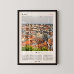 Könnte beinhalten: Gerahmter Druck mit einem Stadtbild von Graz, Österreich, mit roten Ziegeldächern und historischen Gebäuden. Der Druck enthält den Text "GRAZ" und zusätzlichen Text unter dem Bild, vor weißem Hintergrund.