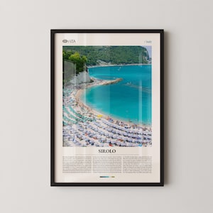 May include: Framed print of Sirolo, Italy, featuring a vibrant turquoise sea and a sandy beach dotted with white umbrellas. The image captures a coastal landscape with a clear sky and a detailed view of the shoreline. The print includes the text "Sirolo".