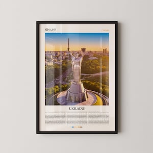 May include: Framed poster showing the Motherland Monument in Kyiv, Ukraine. The statue is a large, stainless steel figure holding a sword and shield, set against a cityscape and sunset. The word "UKRAINE" is printed at the bottom of the poster.