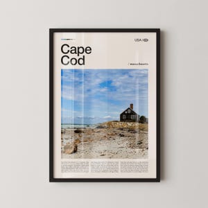 Könnte beinhalten: Gerahmtes Poster mit einer malerischen Ansicht von Cape Cod, Massachusetts, USA. Das Bild zeigt ein kleines, dunkles Haus an einem felsigen Strand unter blauem Himmel mit Wolken. Das Poster trägt oben die Worte "Cape Cod".