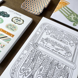 May include: A collection of stationery items, including stickers, cards, and patterned paper. The stickers feature phrases like "On Purpose" and "Not Like the Others." A black and white illustration of sardines in a can is also visible, with the text "Sardines Rares."