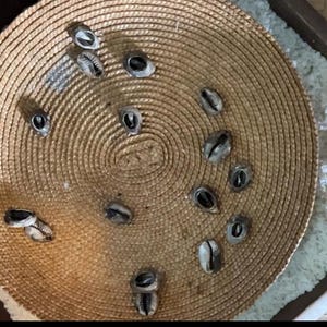 May include: A woven basket with a circular, brown, straw-like surface. The basket is filled with small, white, seashell-like objects.